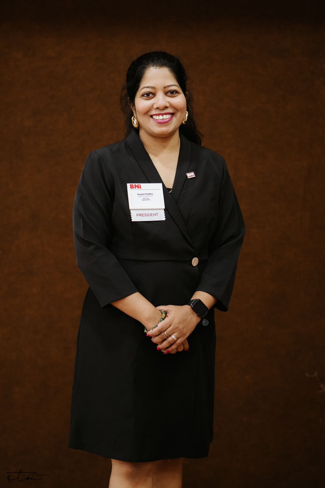 Prachi Prabhu in a black dress, hands clasped, smiling